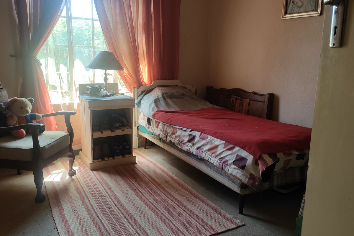 A bedroom featuring a window with security bars and standard interior finishes.