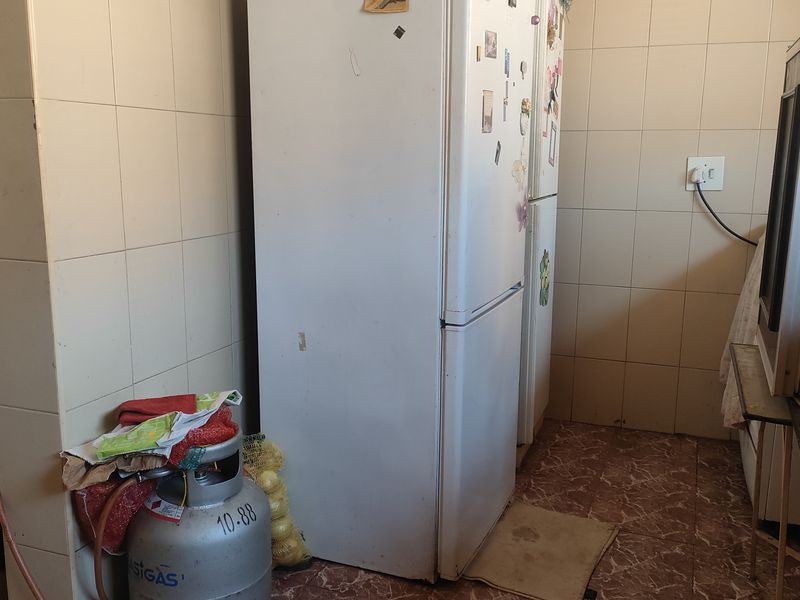 A dated kitchen area featuring tiled walls and flooring, requiring modernization of finishes and layout to improve functionality and aesthetic appeal.