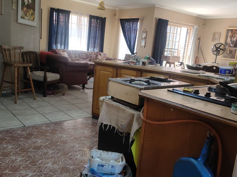 Open plan living and kitchen area featuring a central island with built-in hob and tiled flooring throughout.