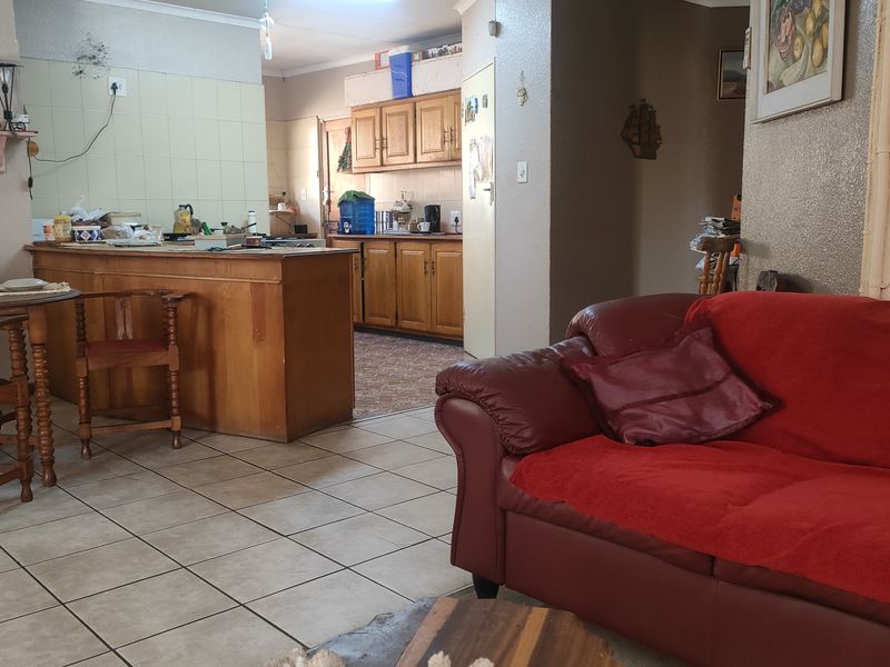 Open plan living and kitchen area featuring tiled flooring and traditional wooden cabinetry, offering a functional layout with potential for modern updates.