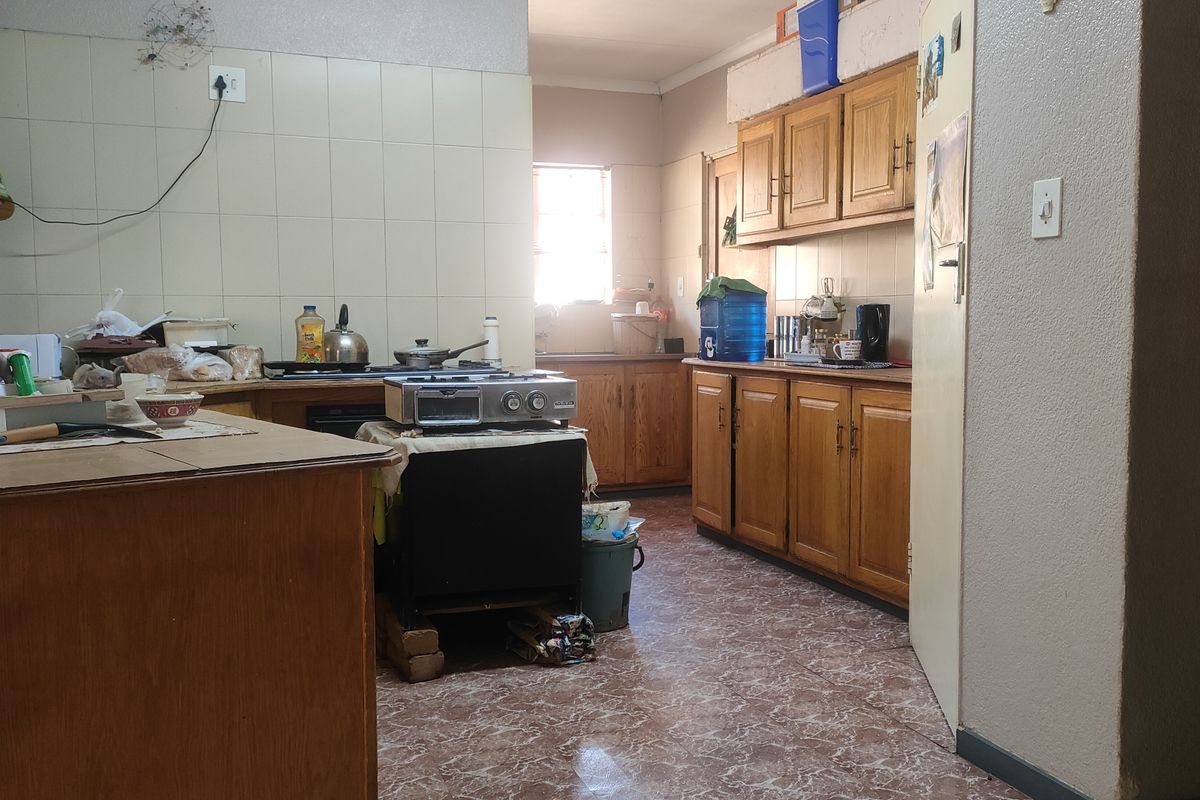 A dated kitchen featuring wooden cabinetry, tiled splashbacks, and tiled flooring, offering significant potential for a modern renovation and aesthetic update.