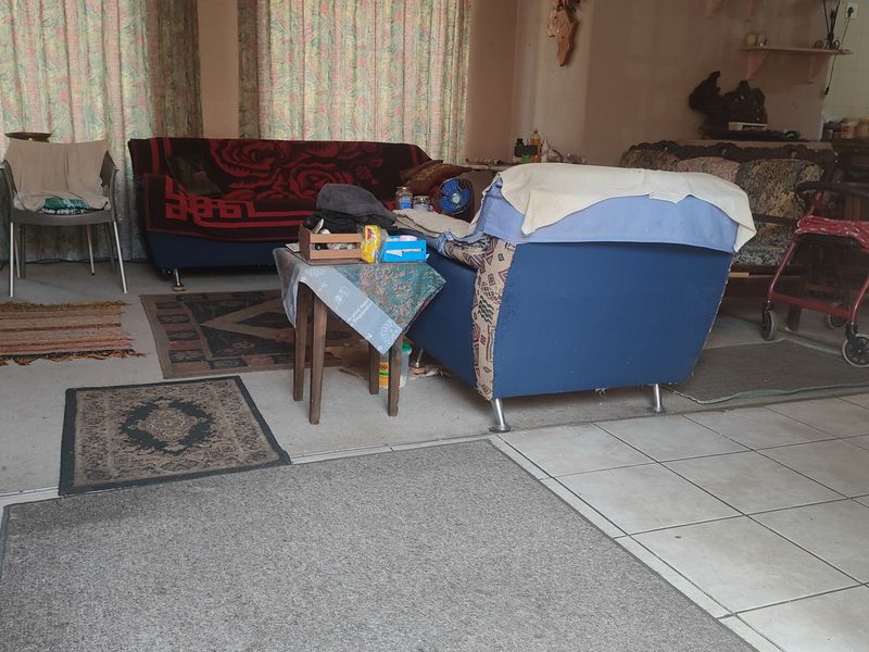 An open-plan living area featuring a combination of tiled and carpeted flooring, providing a functional space for relaxation and daily activities.