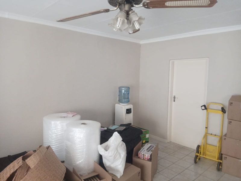 A neutral-toned living area featuring a ceiling fan and tiled flooring, currently vacant and ready for staging.