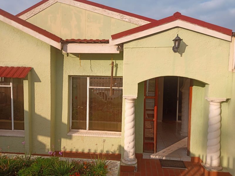 Front facade of a house featuring an arched entrance with decorative spiral columns, tiled porch, and textured exterior walls.