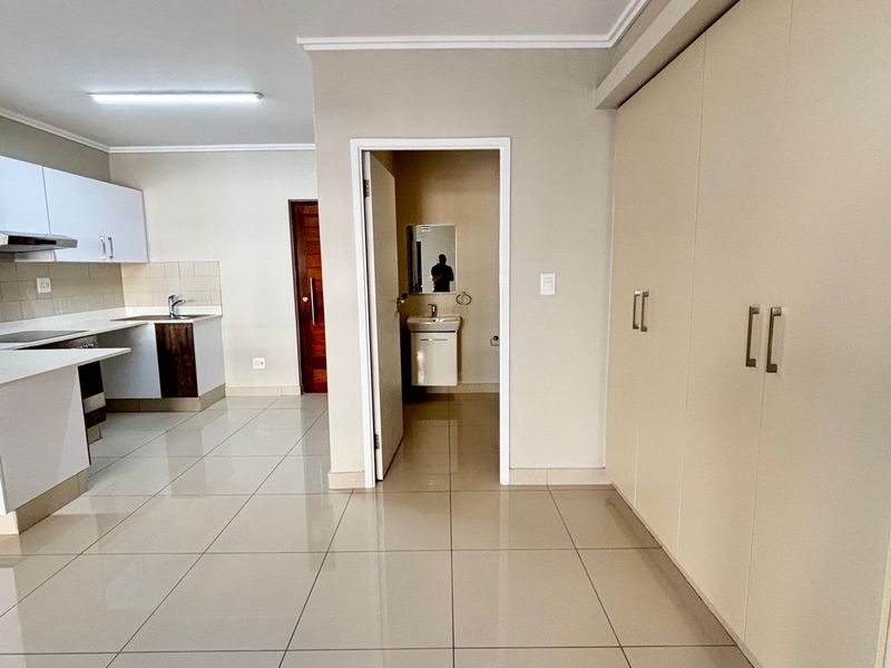 Open plan living area featuring tiled floors, built-in kitchen cabinetry, and access to a separate bathroom with a vanity.