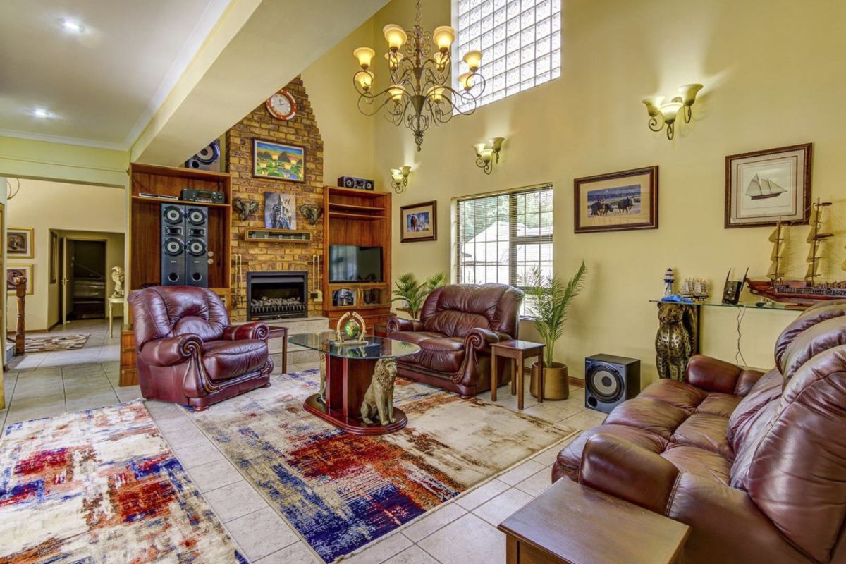 Spacious living room featuring a vaulted ceiling, brick fireplace with built-in shelving, tiled flooring, and a large glass block window for natural light.