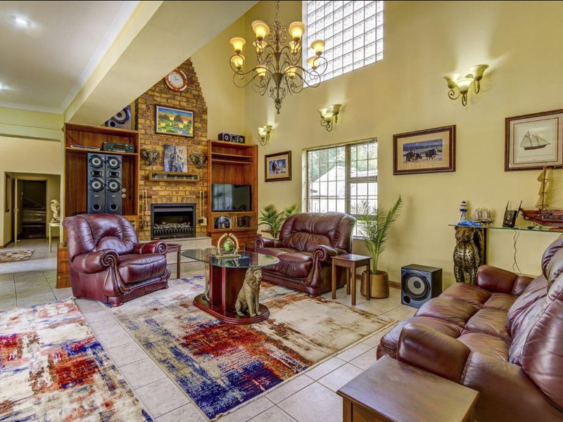 Spacious living room featuring a vaulted ceiling, brick fireplace with built-in shelving, tiled flooring, and a large glass block window for natural light.