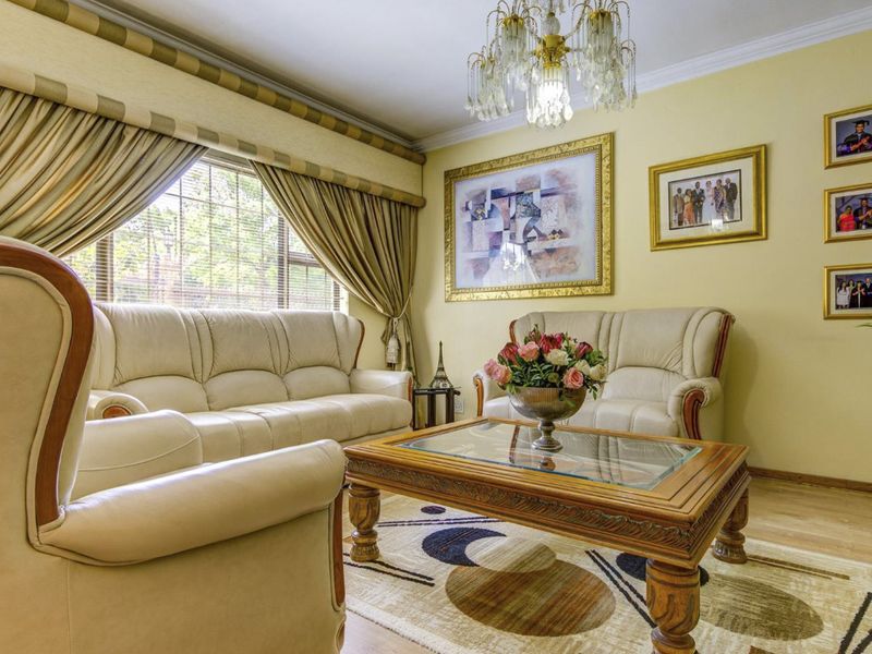 A traditional living room featuring crown molding, laminate flooring, and a central chandelier, offering a comfortable and well-maintained space for relaxation.