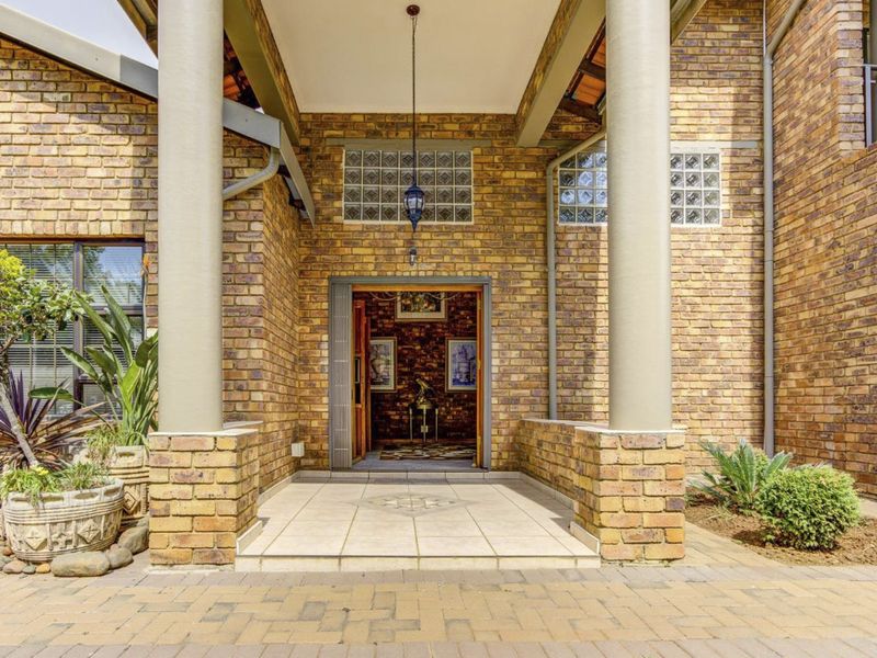 A welcoming front entrance featuring a covered porch, face brick exterior, structural columns, and decorative glass block accents.