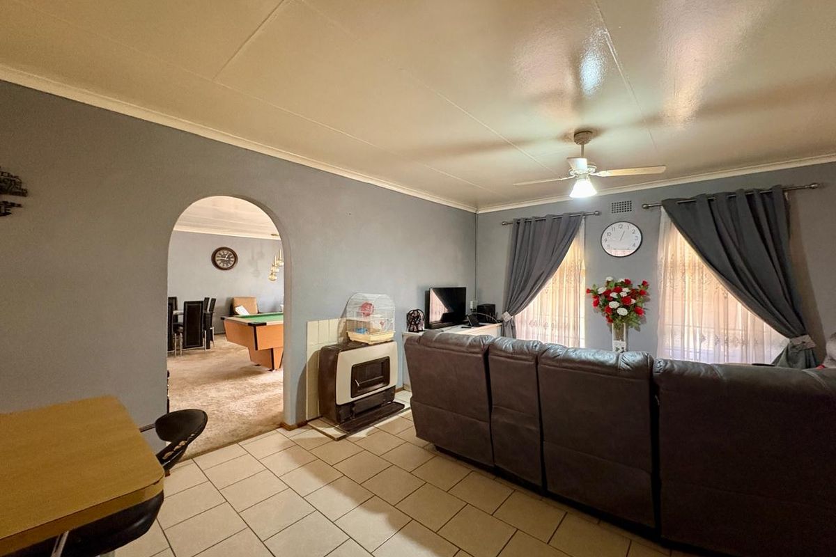 Spacious living room featuring tiled flooring, a ceiling fan, and a built-in gas heater, with an arched entryway leading to an adjacent room.