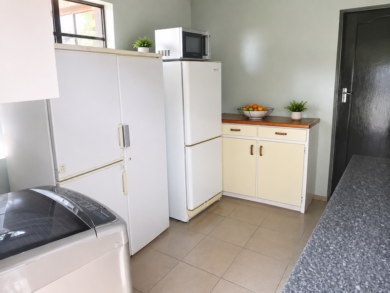 A functional scullery area featuring built-in cabinetry, a timber countertop, and tiled flooring, providing additional storage and utility space.