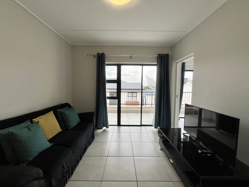 A living room featuring tiled flooring and a sliding glass door that provides access to an outdoor balcony area.