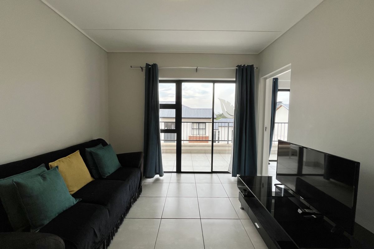 A living room featuring tiled flooring and a sliding glass door that provides access to an outdoor balcony area.