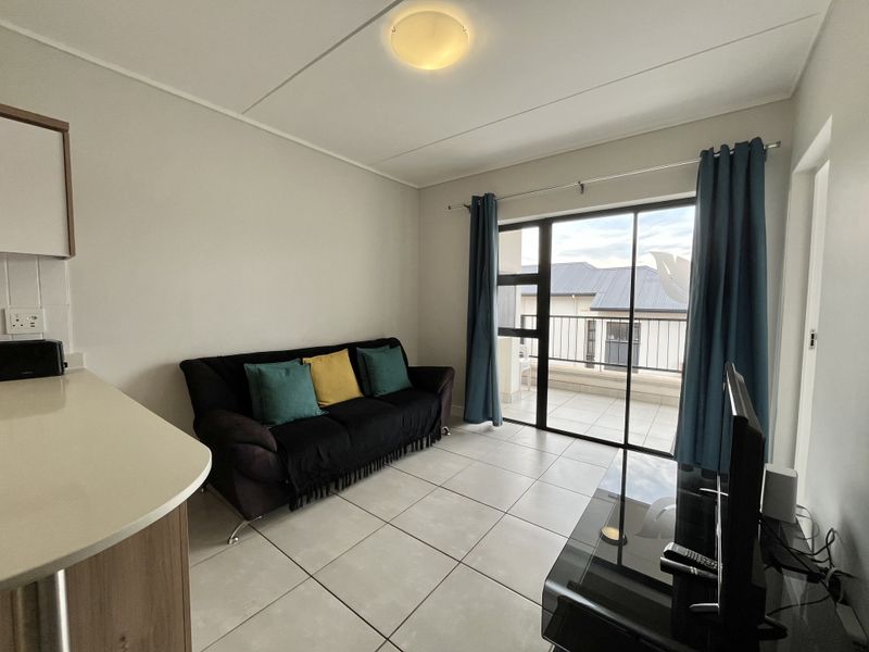 Open plan living area featuring tiled flooring and a large sliding glass door providing access to a balcony.