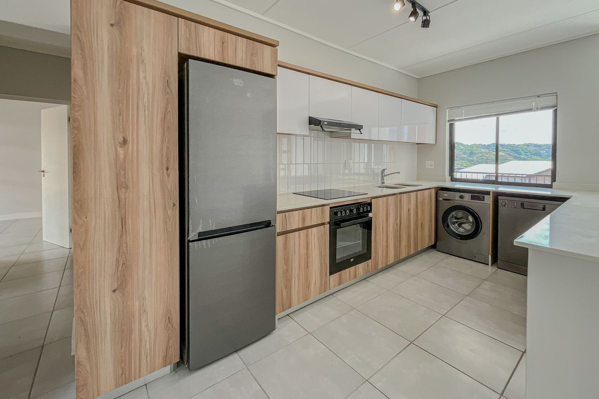 Modern kitchen featuring wood-look and white gloss cabinetry, integrated appliances, electric hob, oven, and tiled flooring with ample natural light.