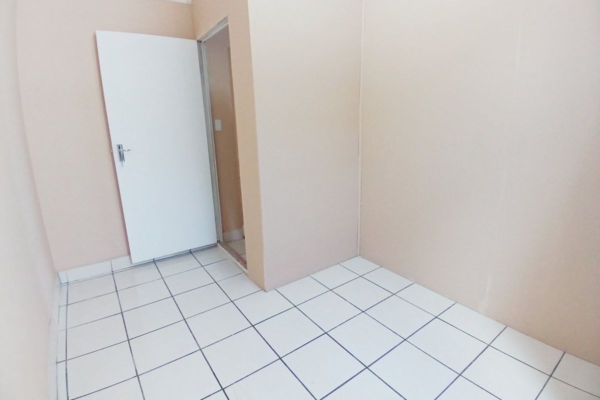 An empty bedroom featuring white tiled flooring and plain walls, providing a blank canvas for potential interior design updates.