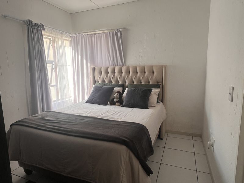 A compact bedroom featuring tiled flooring and natural light from a window with installed curtain rails.