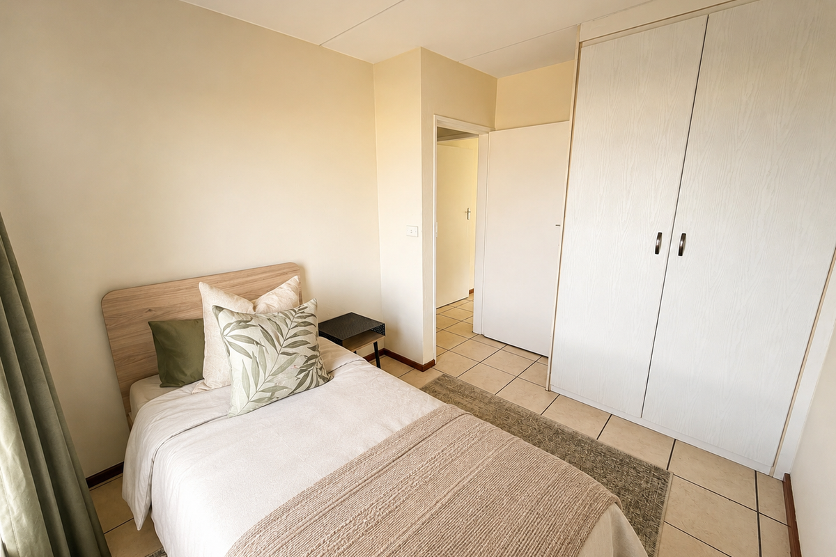 A bedroom featuring neutral walls, tiled flooring, and a built-in wardrobe with light wood-grain finish doors.