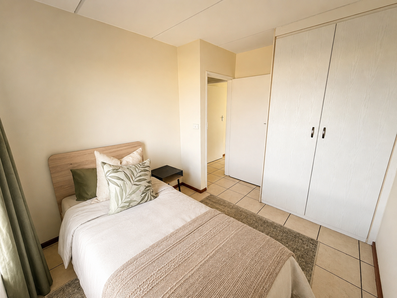 A bedroom featuring neutral walls, tiled flooring, and a built-in wardrobe with light wood-grain finish doors.