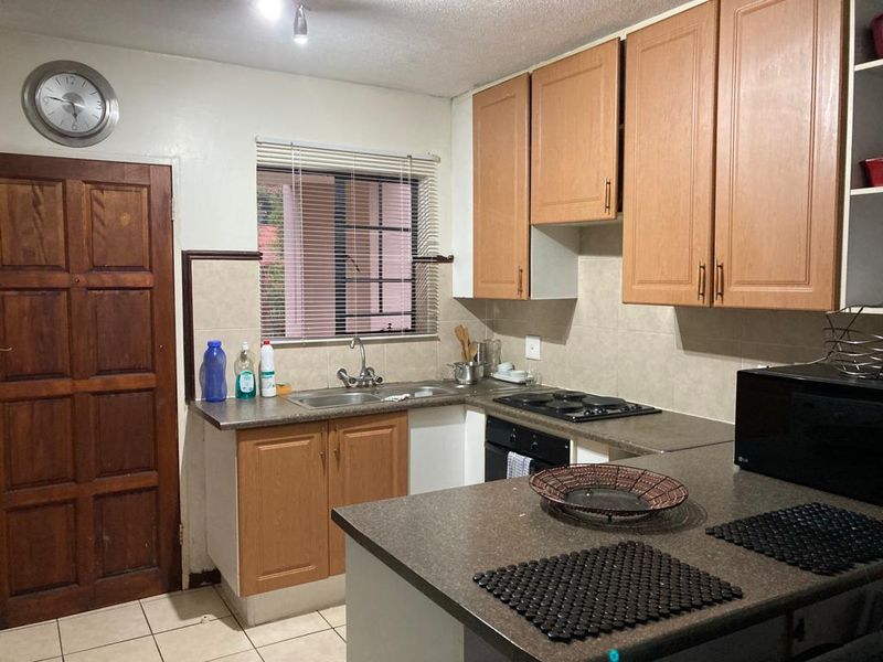 Functional kitchen featuring laminate cabinetry, built-in oven and hob, tiled backsplash, and tiled flooring, offering a practical layout for daily meal preparation.
