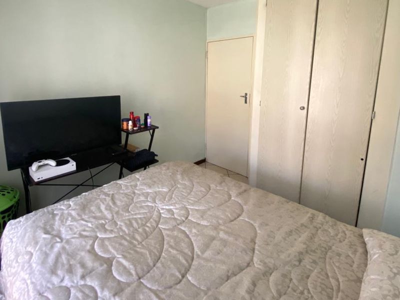 A functional bedroom featuring built-in wardrobe storage and tiled flooring, offering a neutral base for personalization.