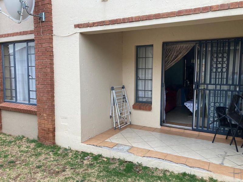 A ground floor patio area featuring tiled flooring, brick accents, and a security gate leading into the apartment interior.