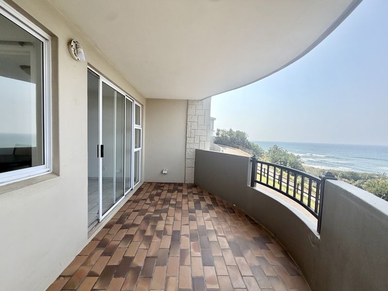 Spacious covered balcony featuring tiled flooring, a metal balustrade, and stunning ocean views, providing an ideal outdoor space for relaxation.
