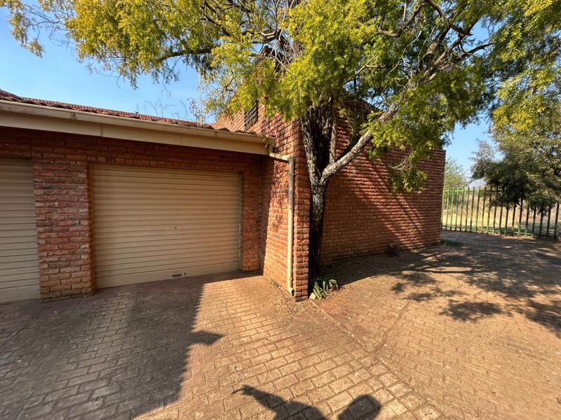 Exterior view of a brick garage featuring a roll-up door and paved driveway area.