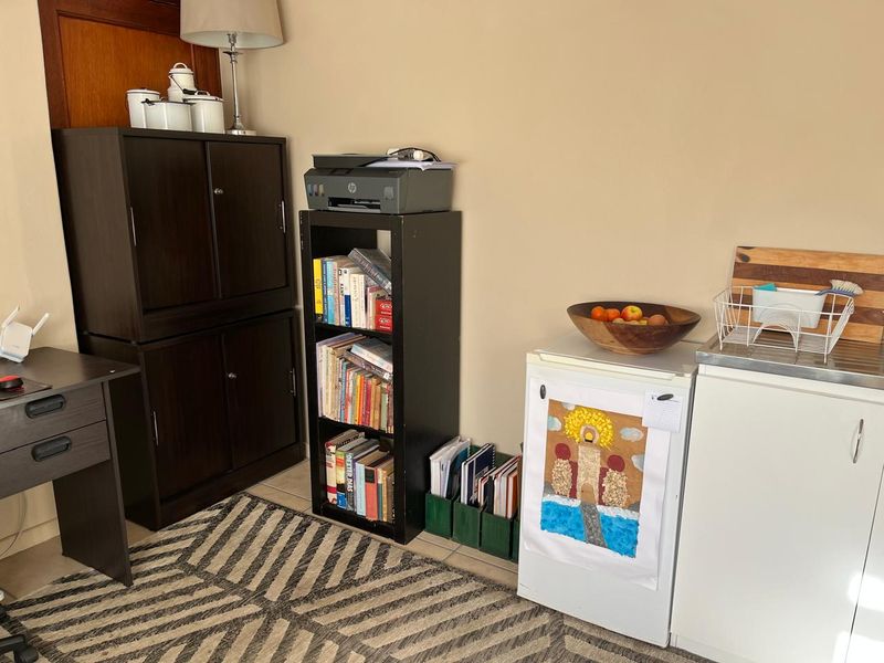 A functional utility area featuring a small refrigerator, sink unit, and tiled flooring, currently utilized for storage and workspace.