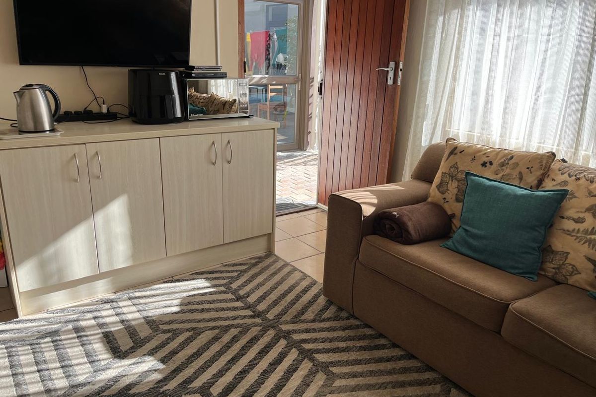A living area featuring built-in cabinetry, tiled flooring, and direct access to an outdoor patio through a timber and glass door.