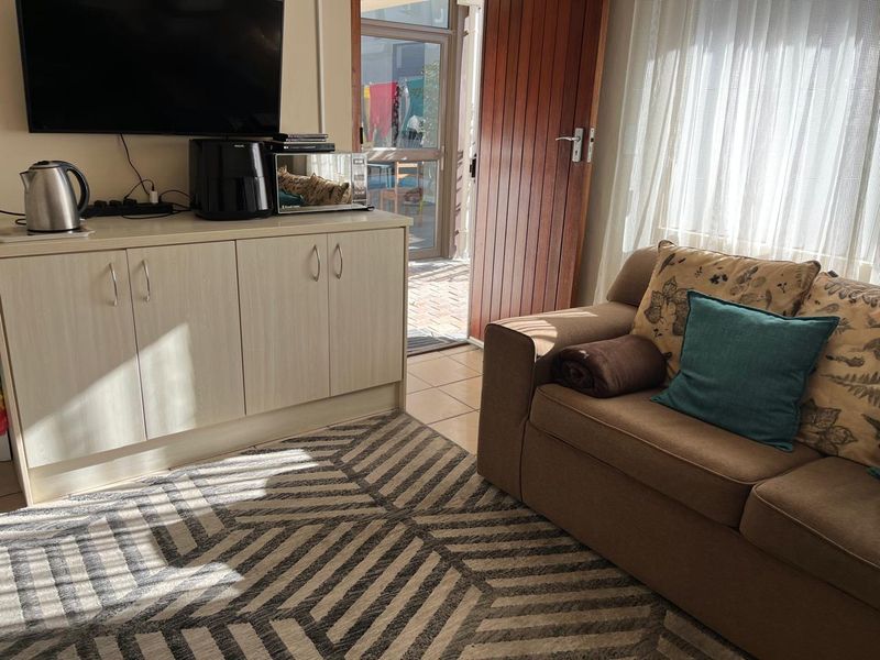 A living area featuring built-in cabinetry, tiled flooring, and direct access to an outdoor patio through a timber and glass door.