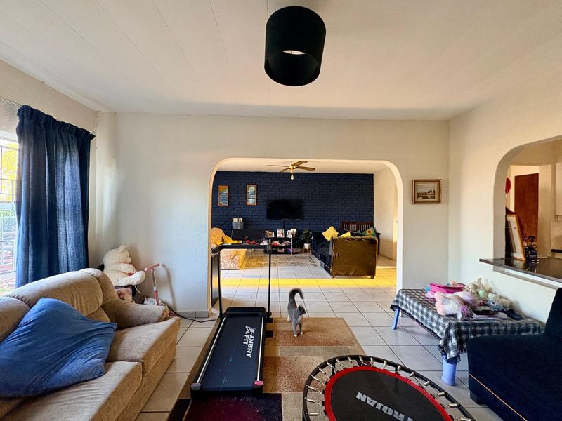 Open plan living area featuring ceramic floor tiles, arched transitions between spaces, and a prominent dark blue exposed brick feature wall.