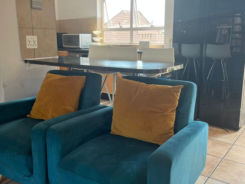 Open plan living and kitchen area featuring tiled flooring, a breakfast bar, and a tiled splashback.