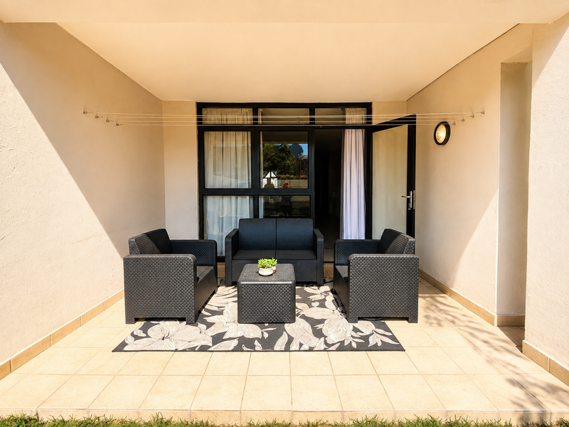 A covered patio area featuring tiled flooring, a wall-mounted light fixture, and a retractable clothesline, providing direct access to the interior through sliding glass doors.