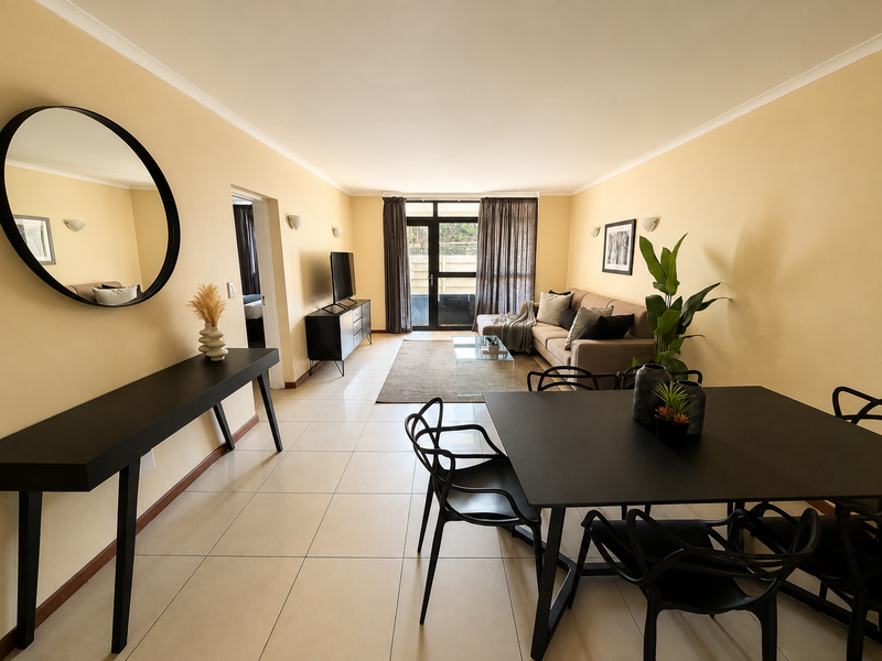 Spacious open-plan living and dining area featuring neutral tiled flooring, modern wall sconces, and direct access to an outdoor space through sliding glass doors.