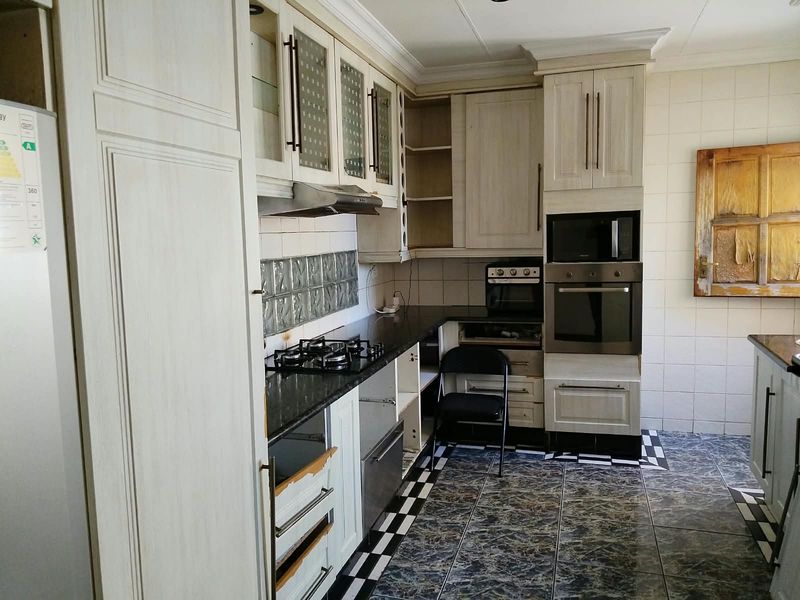 Kitchen featuring built-in cabinetry, granite countertops, and integrated appliances. The space requires cosmetic updates and repairs to cabinetry to restore its functionality and appeal.