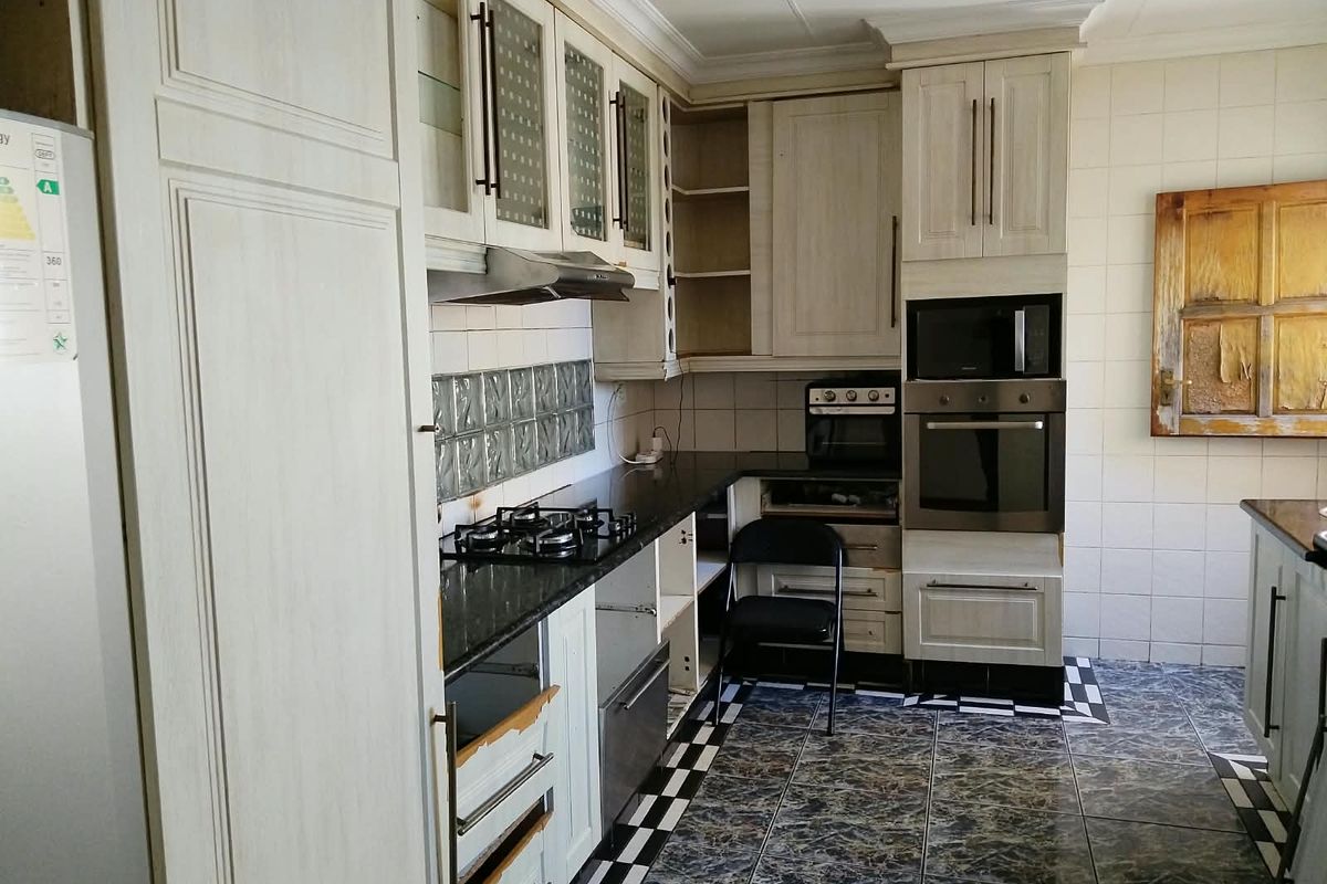 Kitchen featuring built-in cabinetry, granite countertops, and integrated appliances. The space requires cosmetic updates and repairs to cabinetry to restore its functionality and appeal.