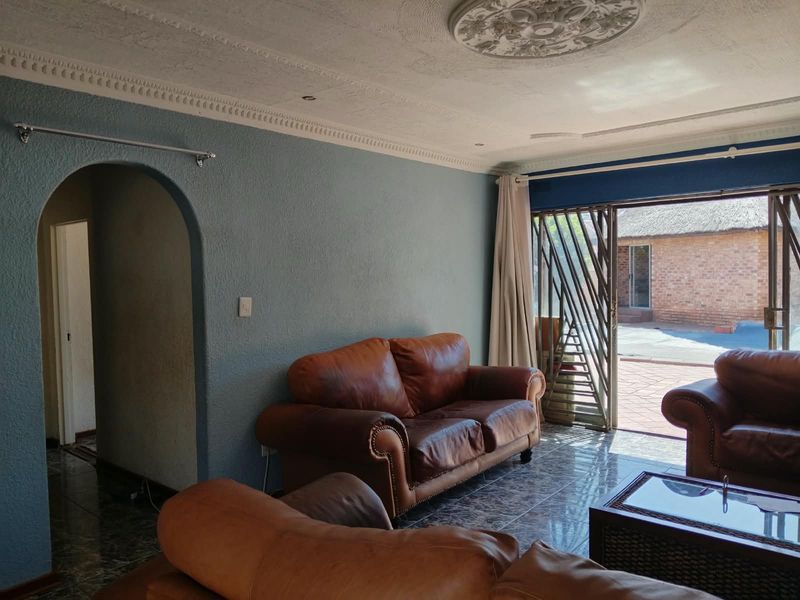 Living room featuring tiled flooring, decorative ceiling detailing, and an arched entryway, with direct access to an outdoor patio area through sliding glass doors.