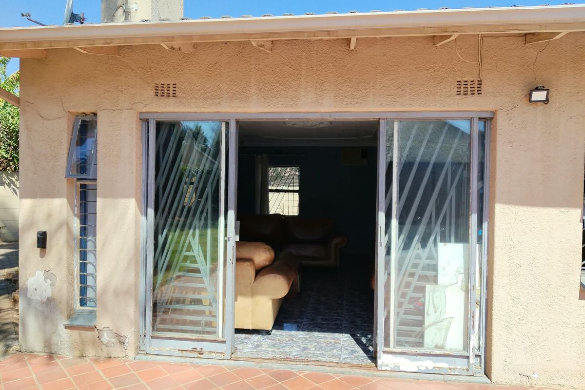 Rear exterior view of the property featuring a tiled patio area and sliding glass doors leading into the living space.