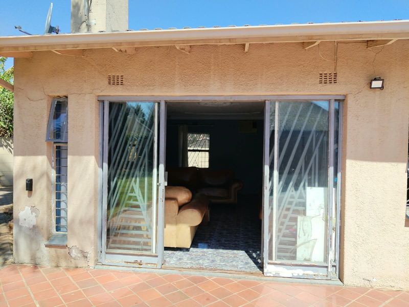 Rear exterior view of the property featuring a tiled patio area and sliding glass doors leading into the living space.