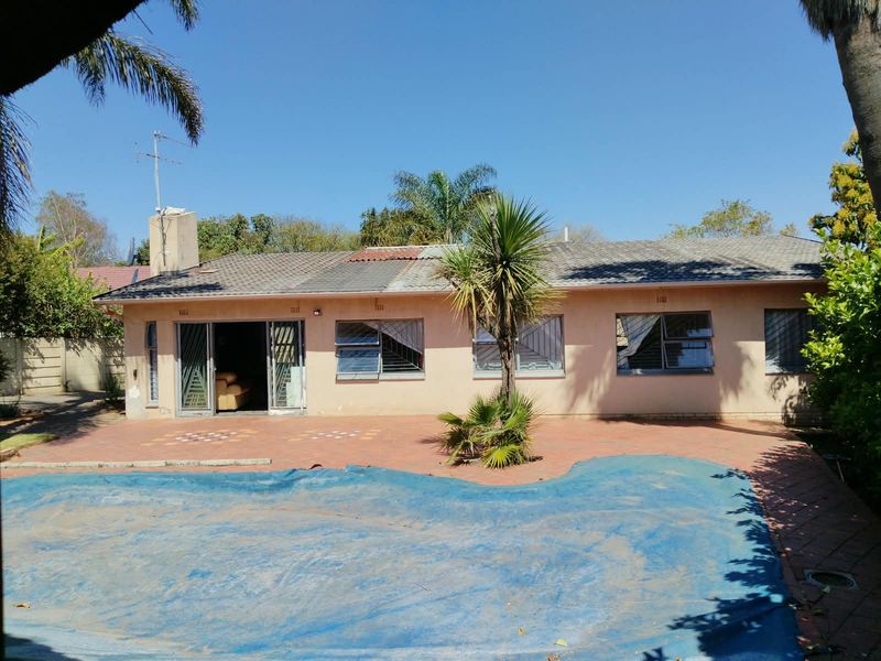 Rear view of the house featuring a paved patio area, a swimming pool with a cover, and direct access through sliding glass doors.