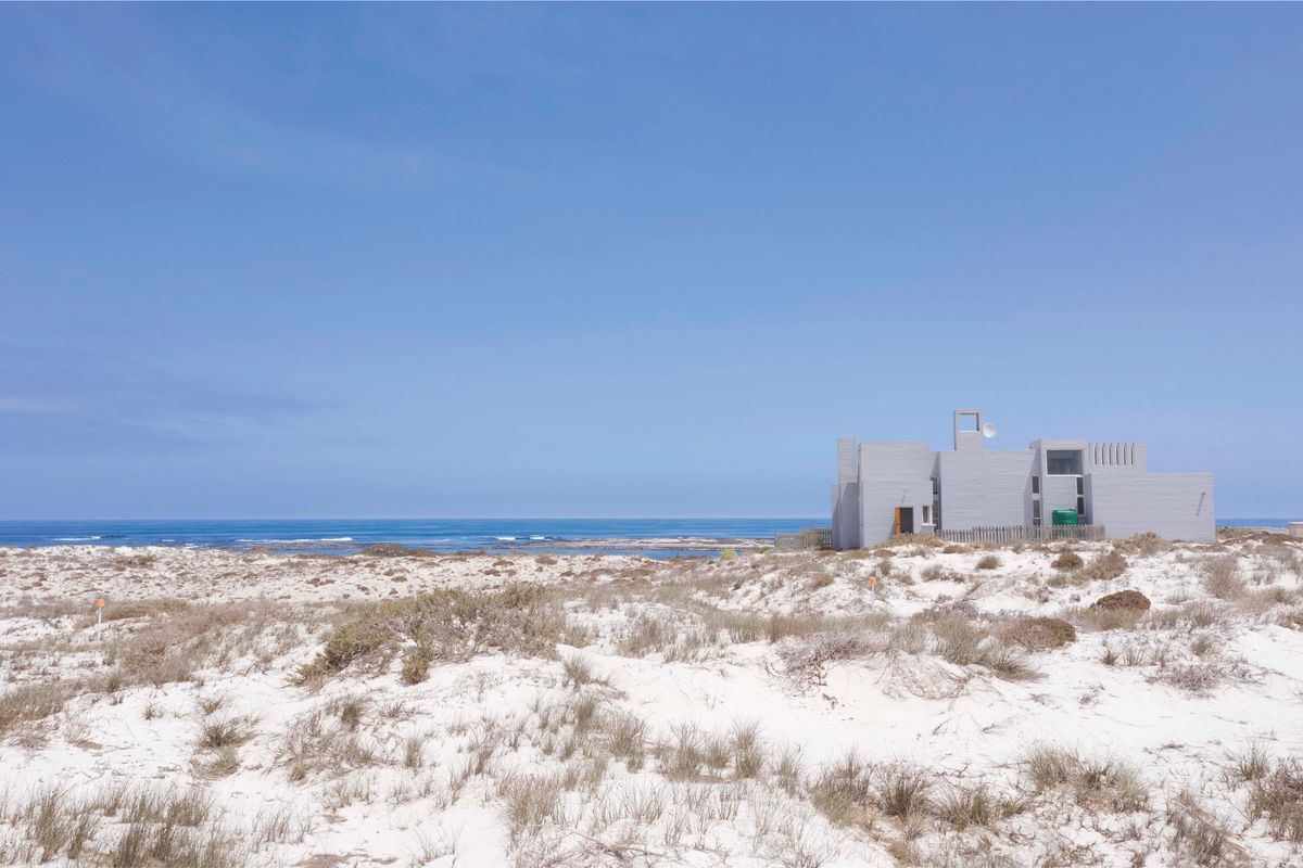 A view of a coastal residential property situated amongst natural sand dunes with direct ocean views.