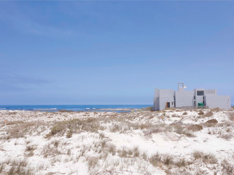 A view of a coastal residential property situated amongst natural sand dunes with direct ocean views.