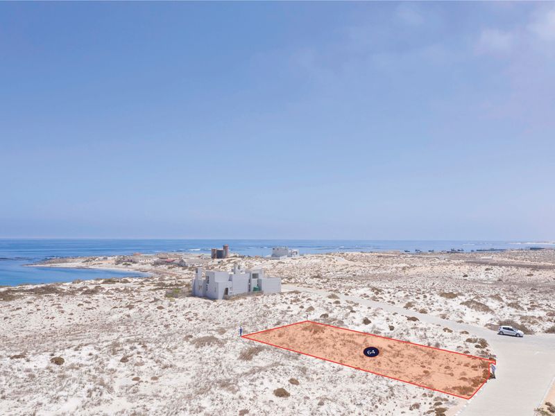 An aerial view of a vacant residential plot located in a coastal area, featuring direct road access and proximity to the ocean.