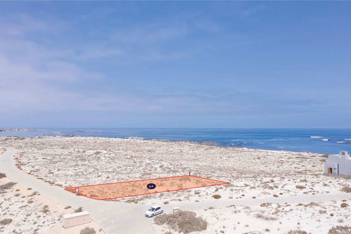 Aerial view of a vacant residential plot located in a coastal estate, featuring direct road access and proximity to the ocean.