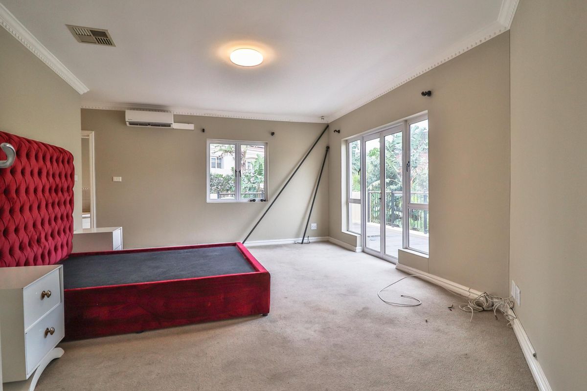 Spacious bedroom featuring neutral walls, crown molding, carpet flooring, air conditioning, and sliding glass doors leading to an outdoor balcony area.