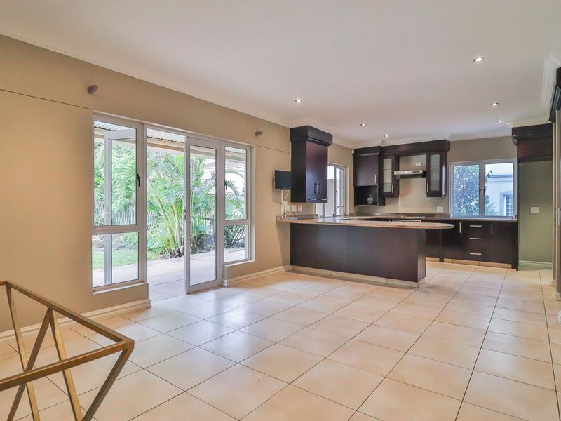 Spacious open-plan living and kitchen area featuring tiled floors, dark wood cabinetry, and large sliding doors providing seamless access to the outdoor patio.