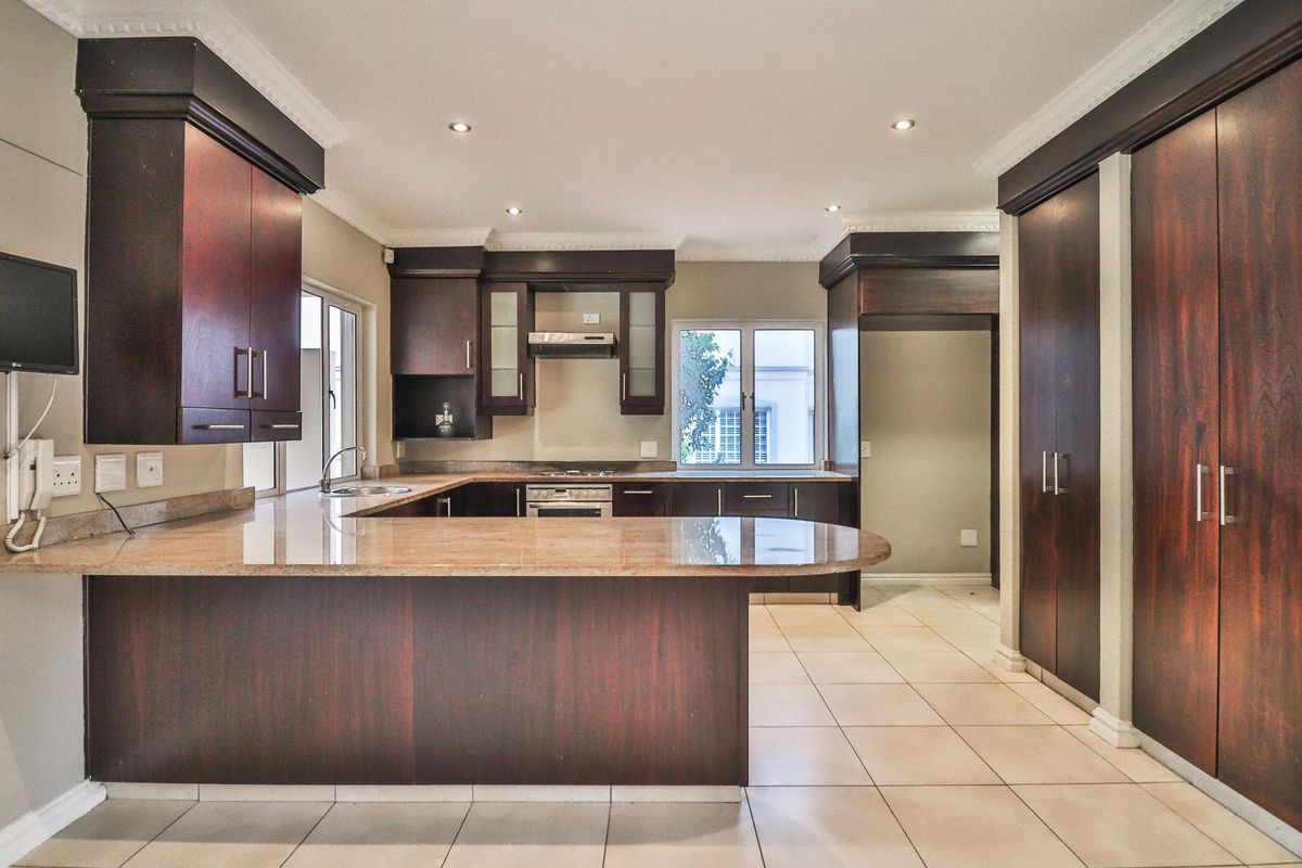 Spacious kitchen featuring dark wood cabinetry, granite countertops, built-in oven, gas hob, and tiled flooring with recessed lighting.