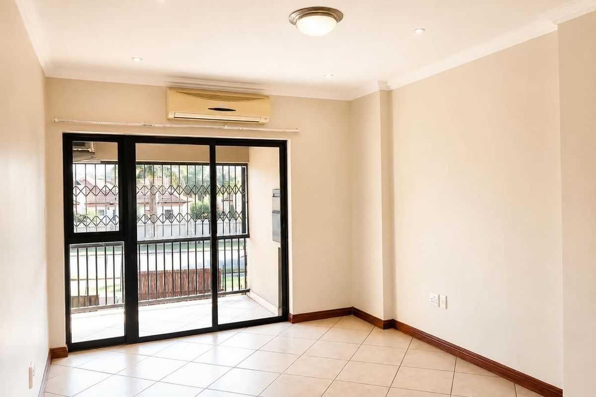 A bright, empty living room featuring tiled floors, recessed lighting, and a sliding glass door leading to a balcony with security gates.