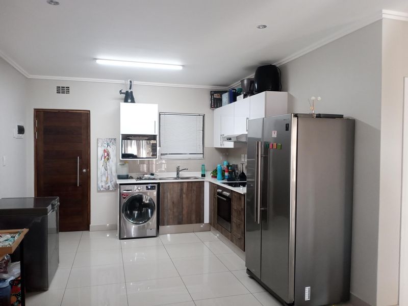 A functional kitchen featuring modern cabinetry, built-in oven and hob, stainless steel sink, and tiled flooring, providing a clean and practical workspace.